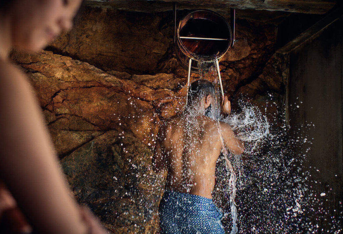 man at a nordic spa tipping a bucket of water on his head