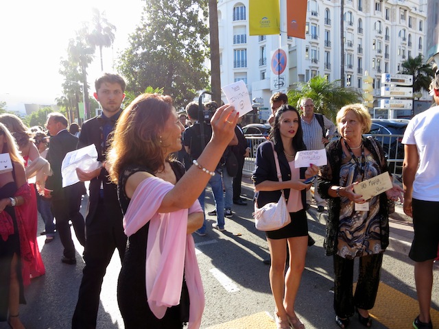 People holding invitation signs at Cannes