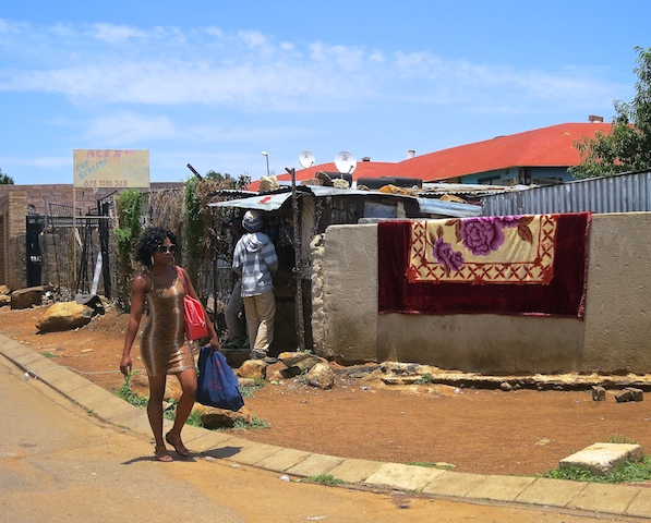 Soweto street scene with woman carrying bags.