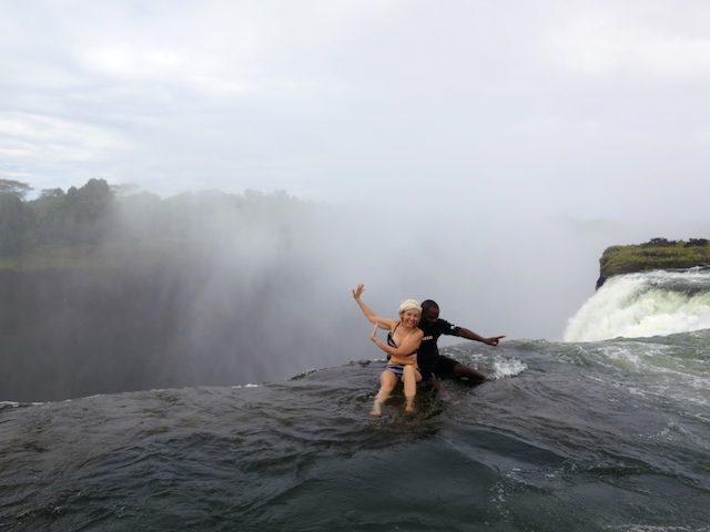 Two people sitting in Devil's Pool at the edge of Victoria Falls in Zambia