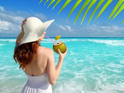 woman drinking coconut on a turquoise tropical beach