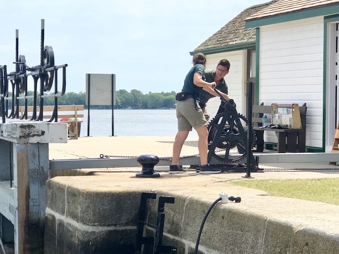 Canada Parks lockkeepers hand cranking the lock gates on the Rideau Canal