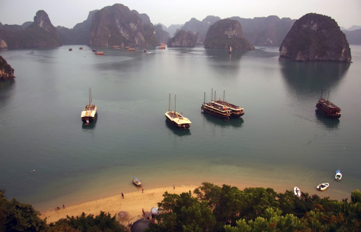 quiet beach in halong bay with karst formations behind