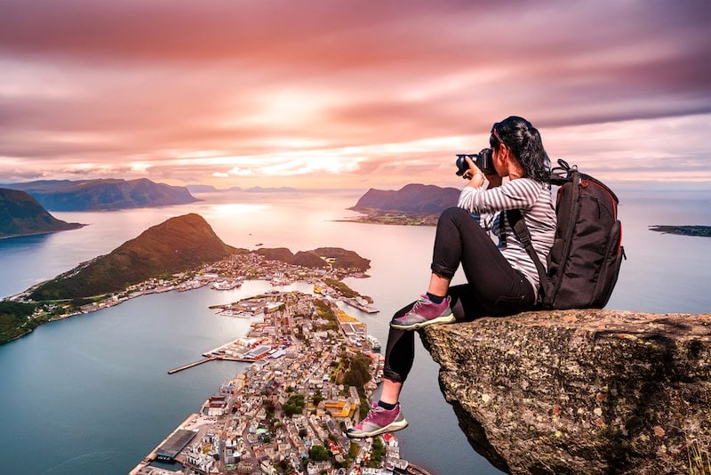 girl with backpack sitting on a cliff