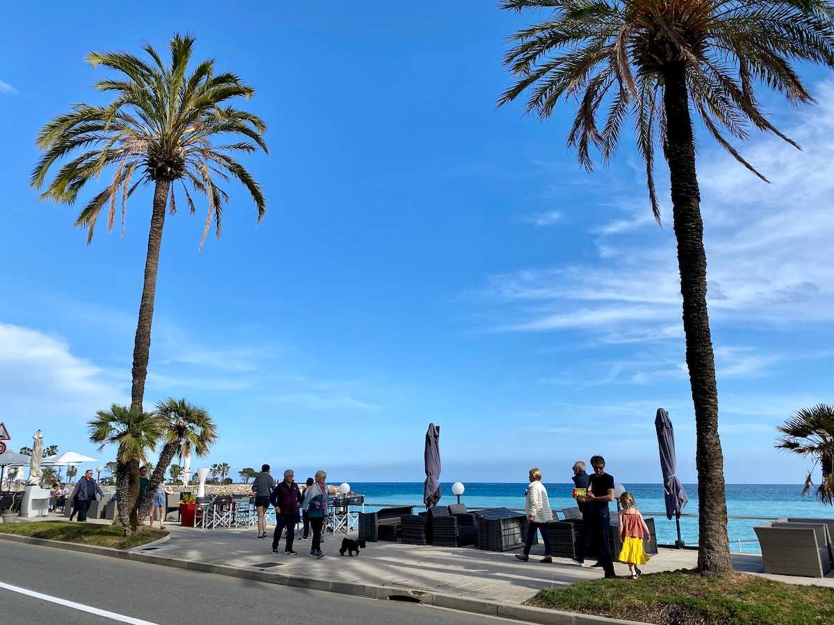 Beach promenade in Menton with palm trees.