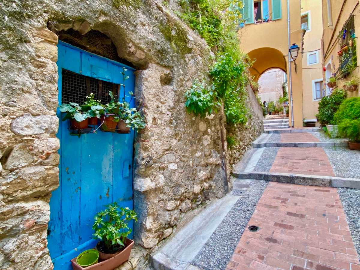Bright blue door on cobblestone lane.