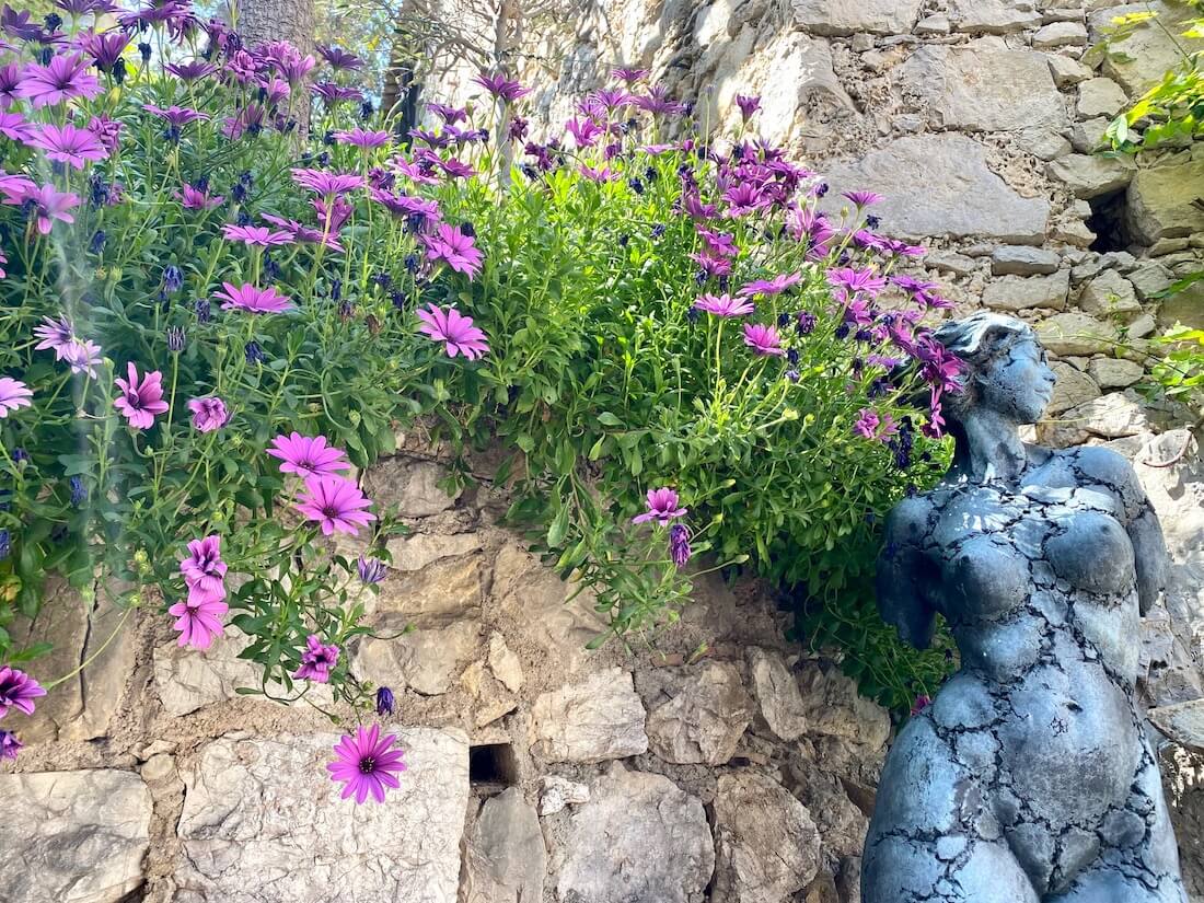 Sculpture of a female and pink flowers growing out of stone walls