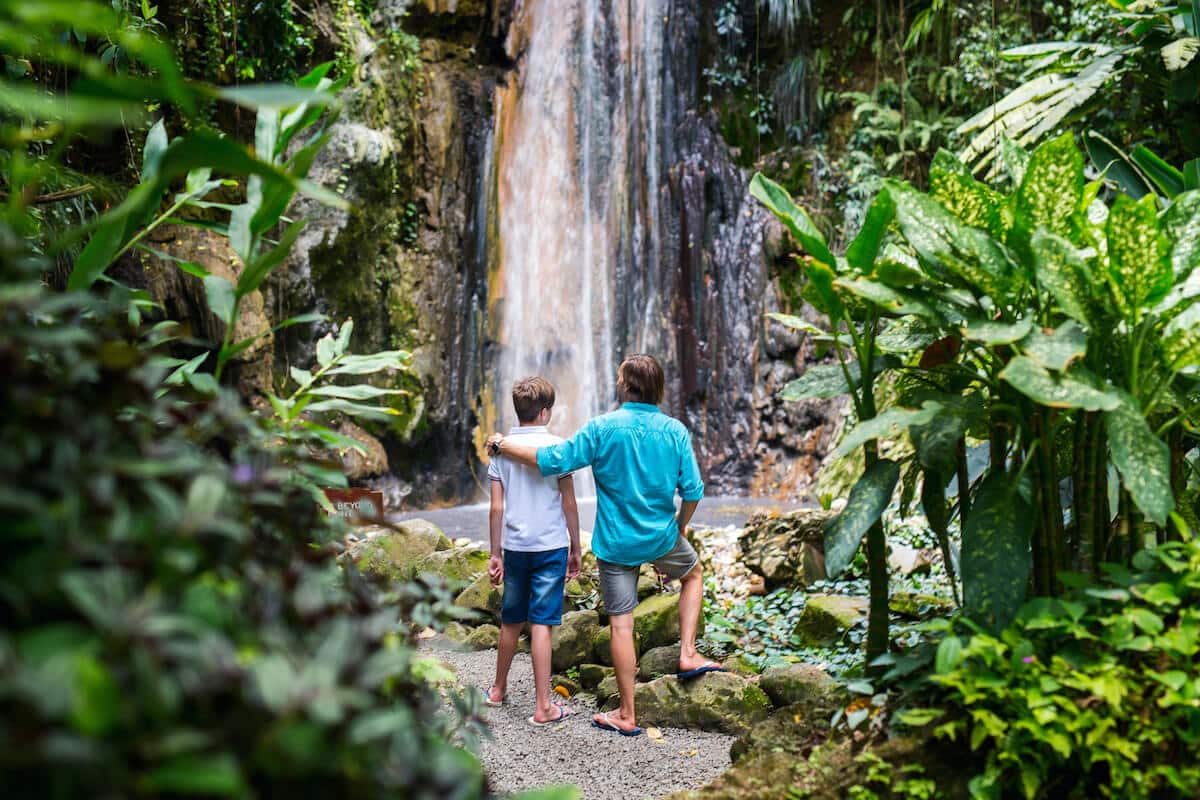 Man and son standing in front of the Diamond Waterfall on the island of St. Lucia