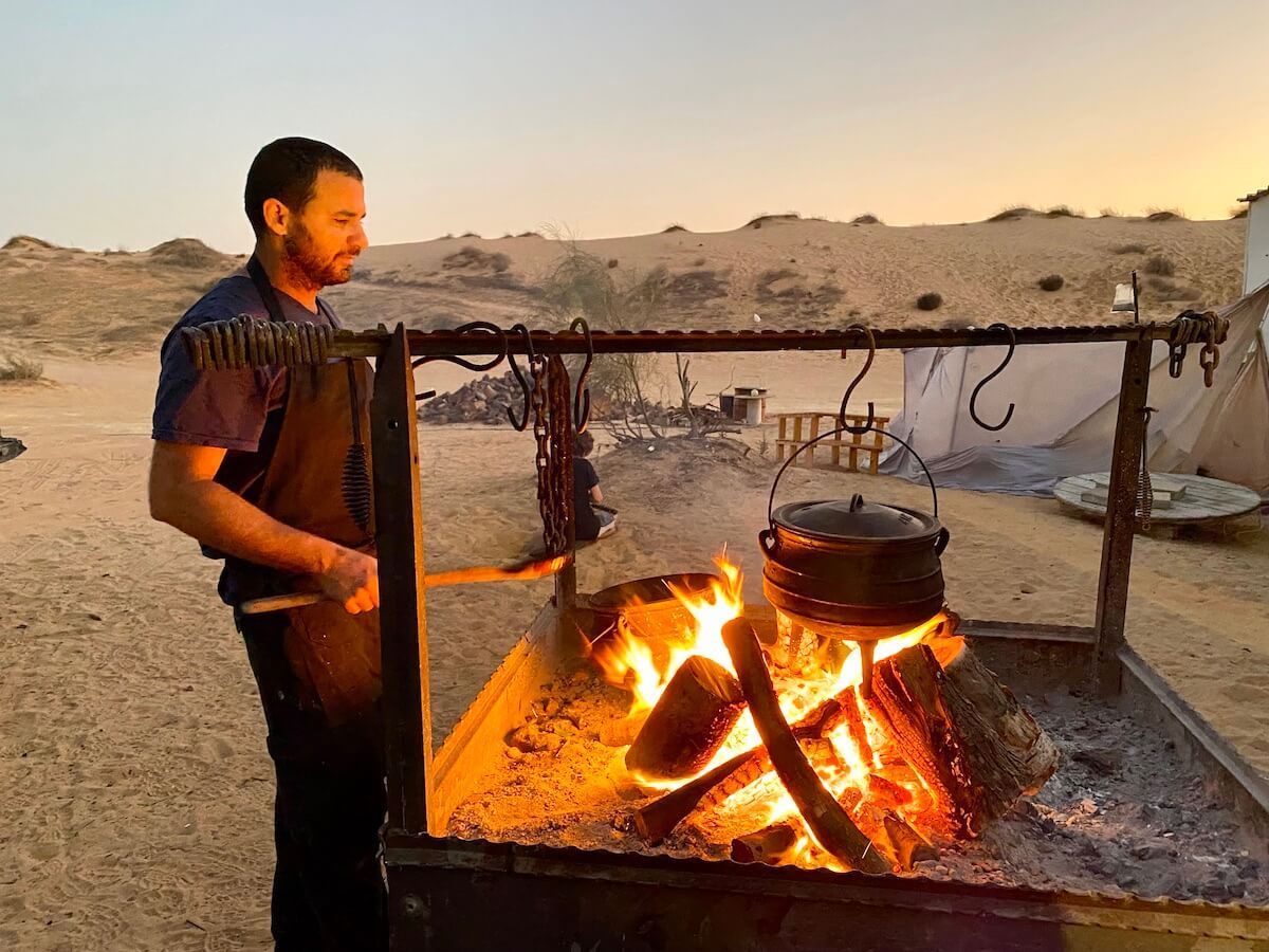 Chef cooking over an open fire in potjie pots