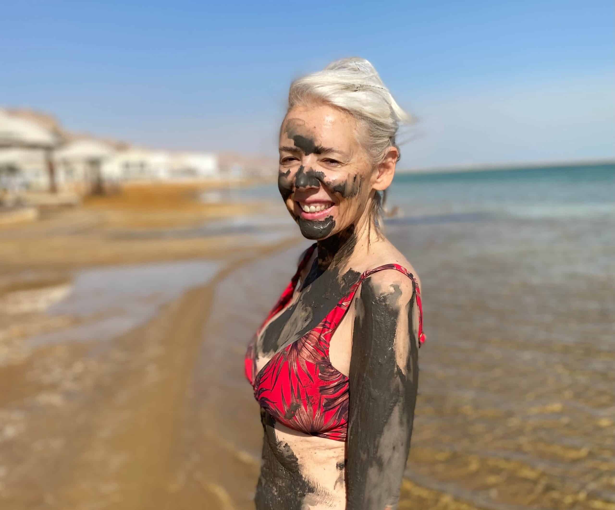 Woman in red bikini covered in mud at the Dead Sea