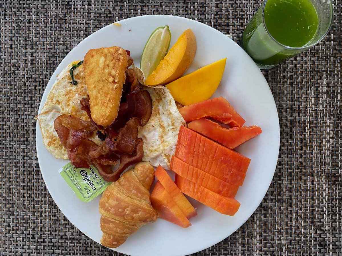 Breakfast with green juice, fruit and bacon.